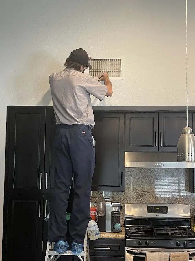 Technician inspecting an air vent during HVAC service in Wawayanda